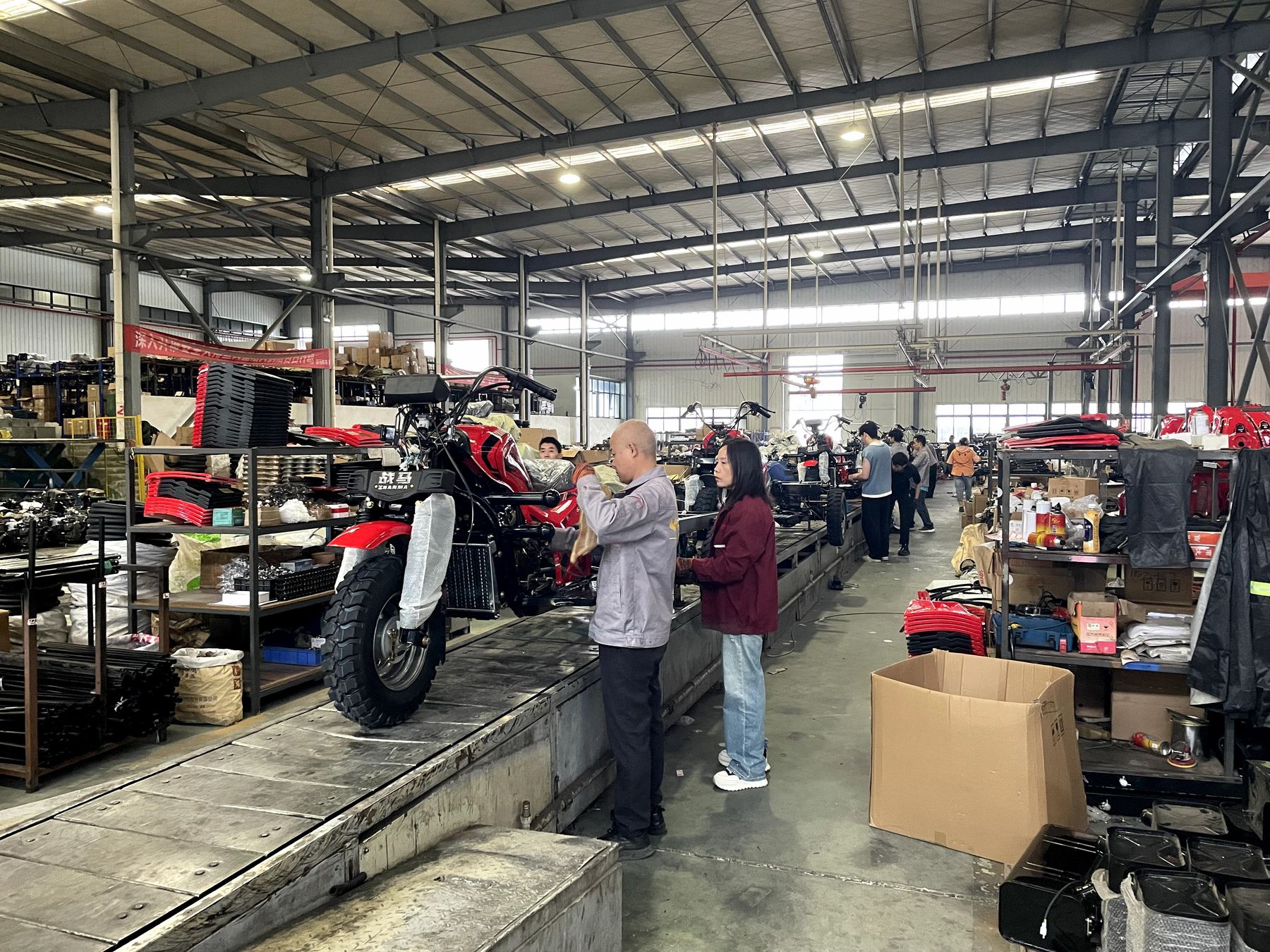 Workers assembling a red tricycle on the production line