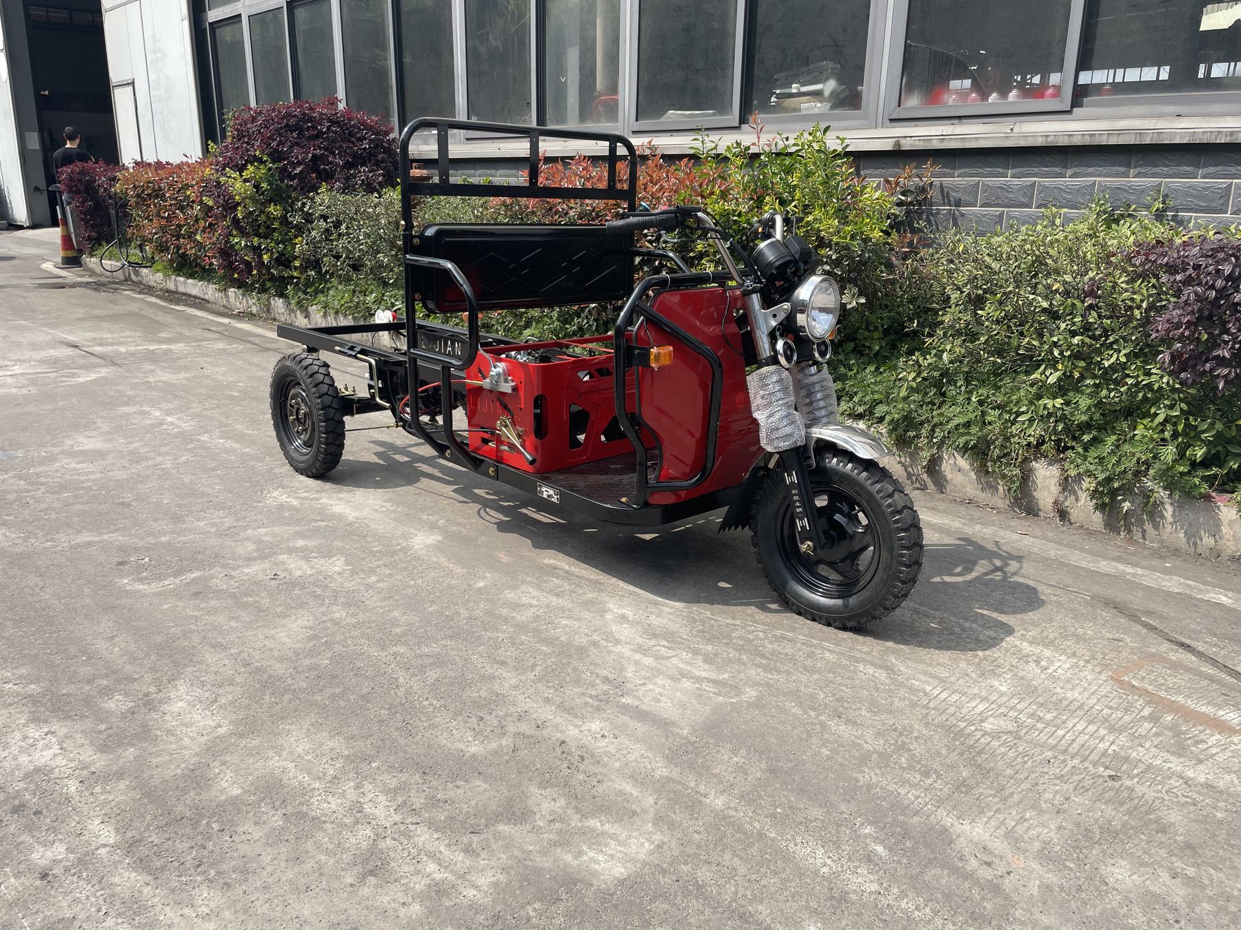 Semi-finished red tricycle frame outside the workshop