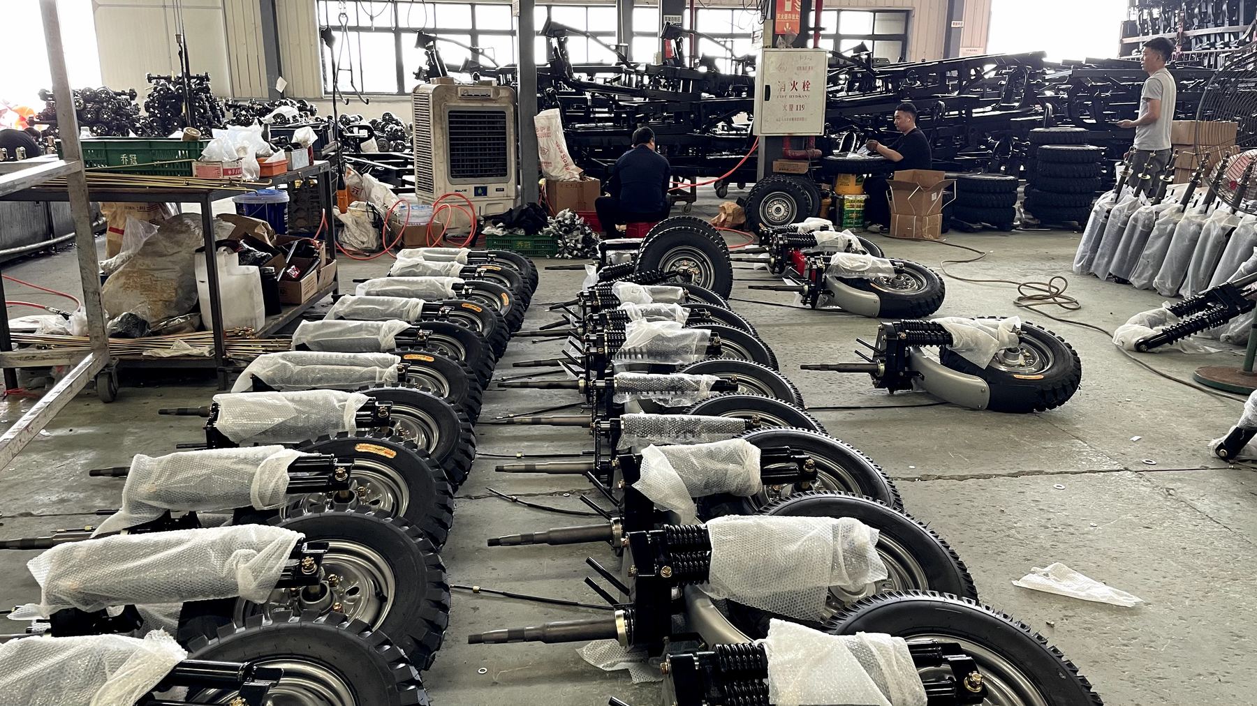 Rows of tricycle wheels and suspension units ready for assembly